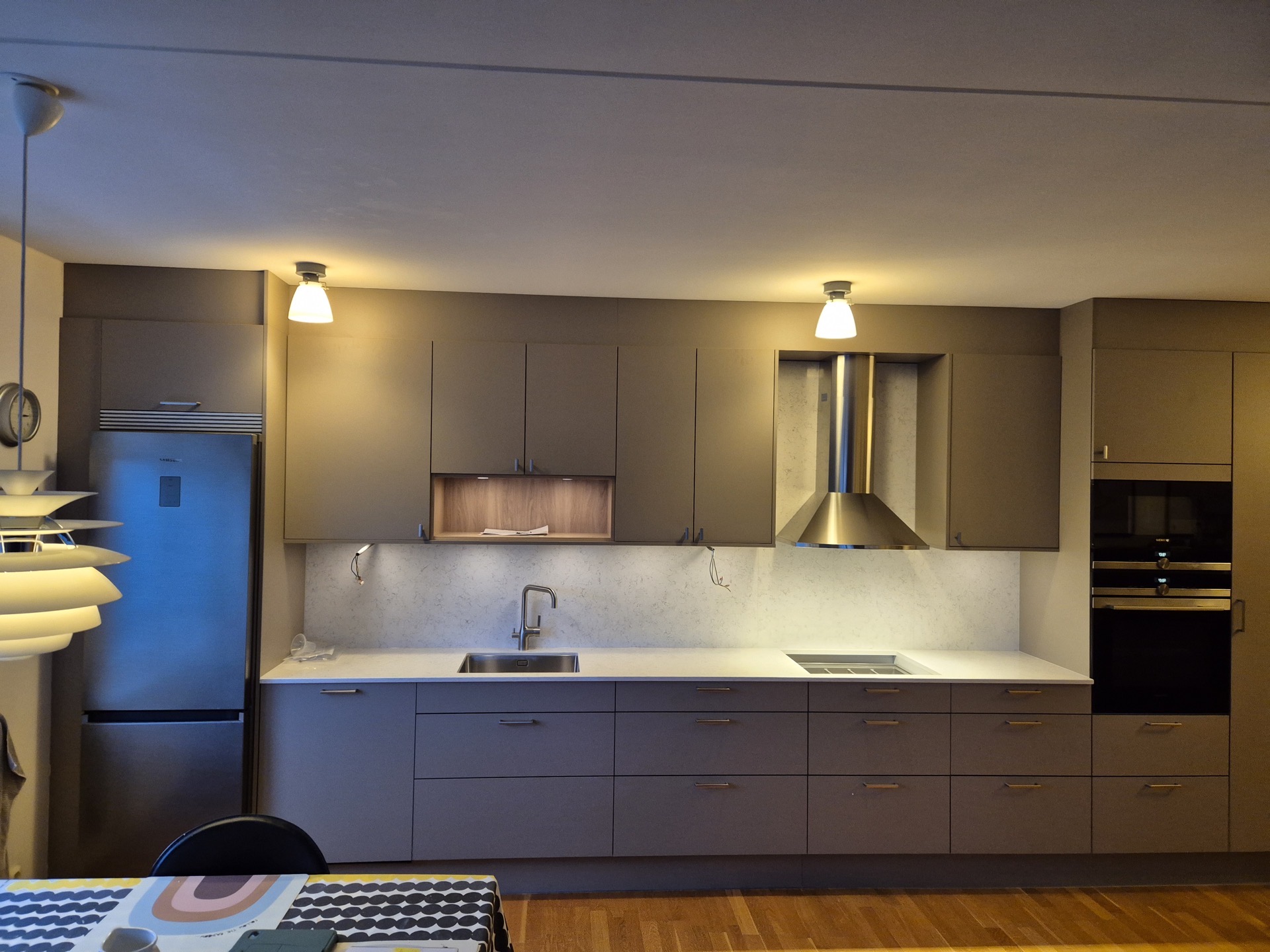 Renoverat kök med mörkgrå/taupe luckor och rostfri köksfläkt